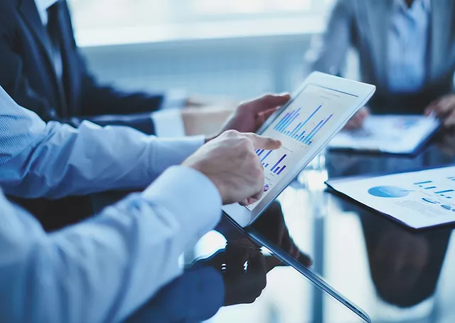 Hands holding a tablet with bar charts during a business meeting